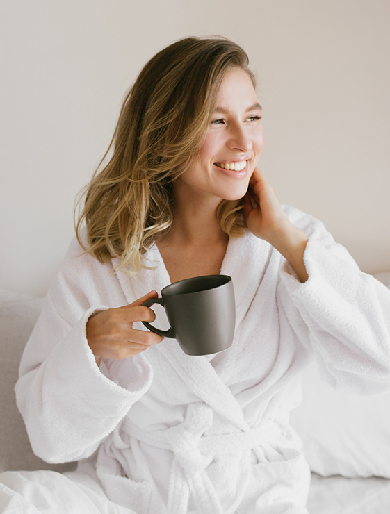 a woman in a white robe holding a coffee cup