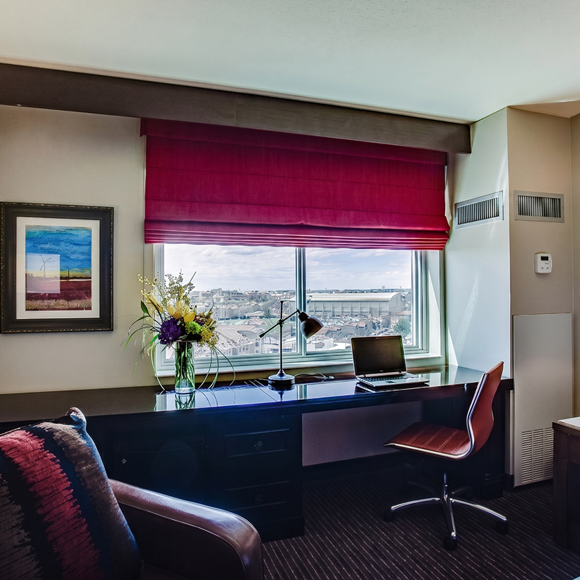a desk with a laptop and a vase of flowers in front of a window