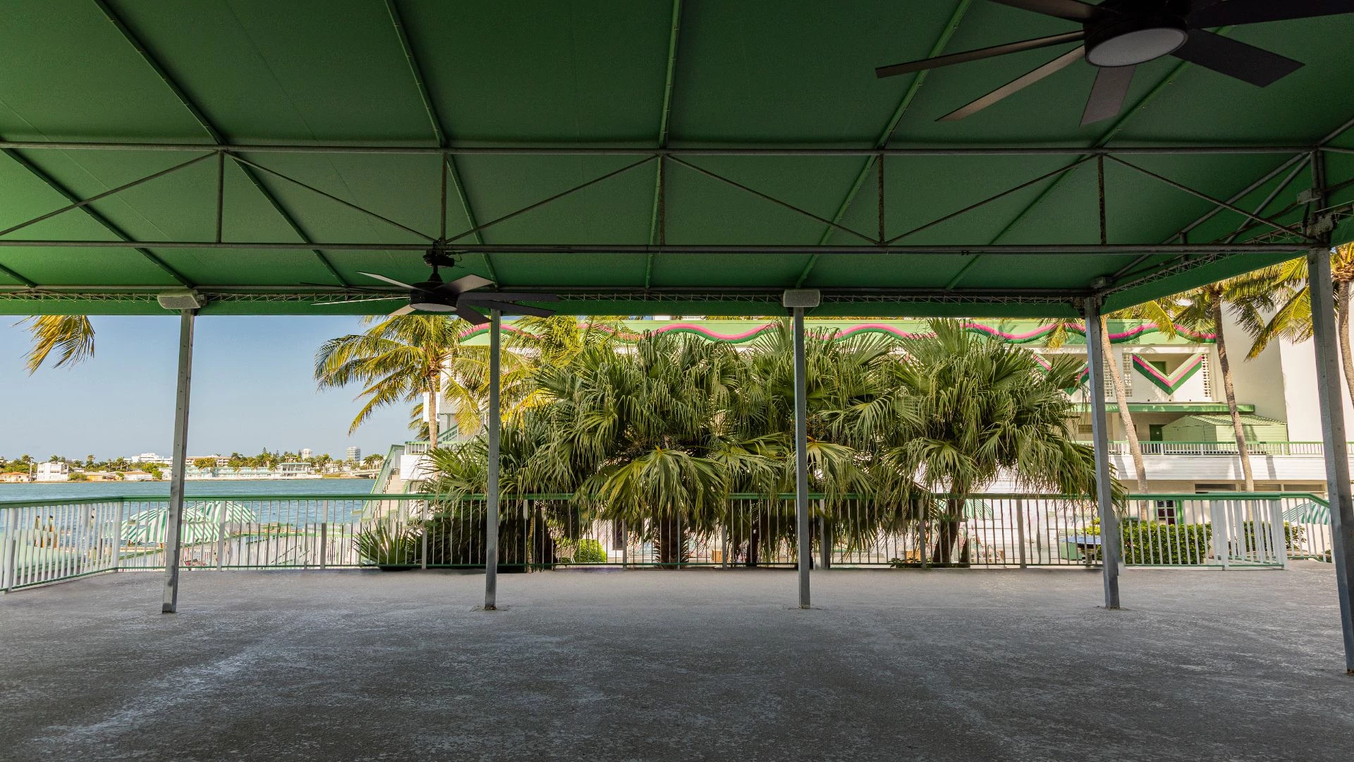 a covered patio with a fan and palm trees