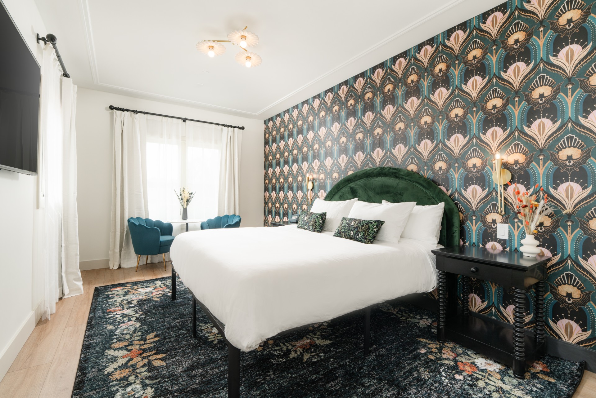 A wide view of a guest room with a white bed, floral wallpaper, and blue accents.