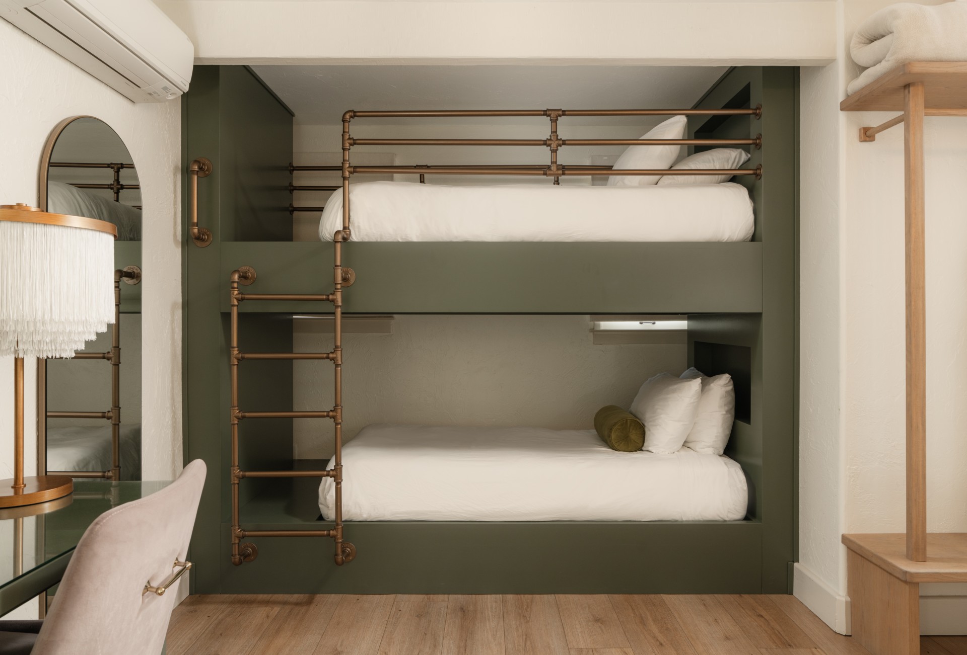 A room with two bunk beds, a desk, and a mirror