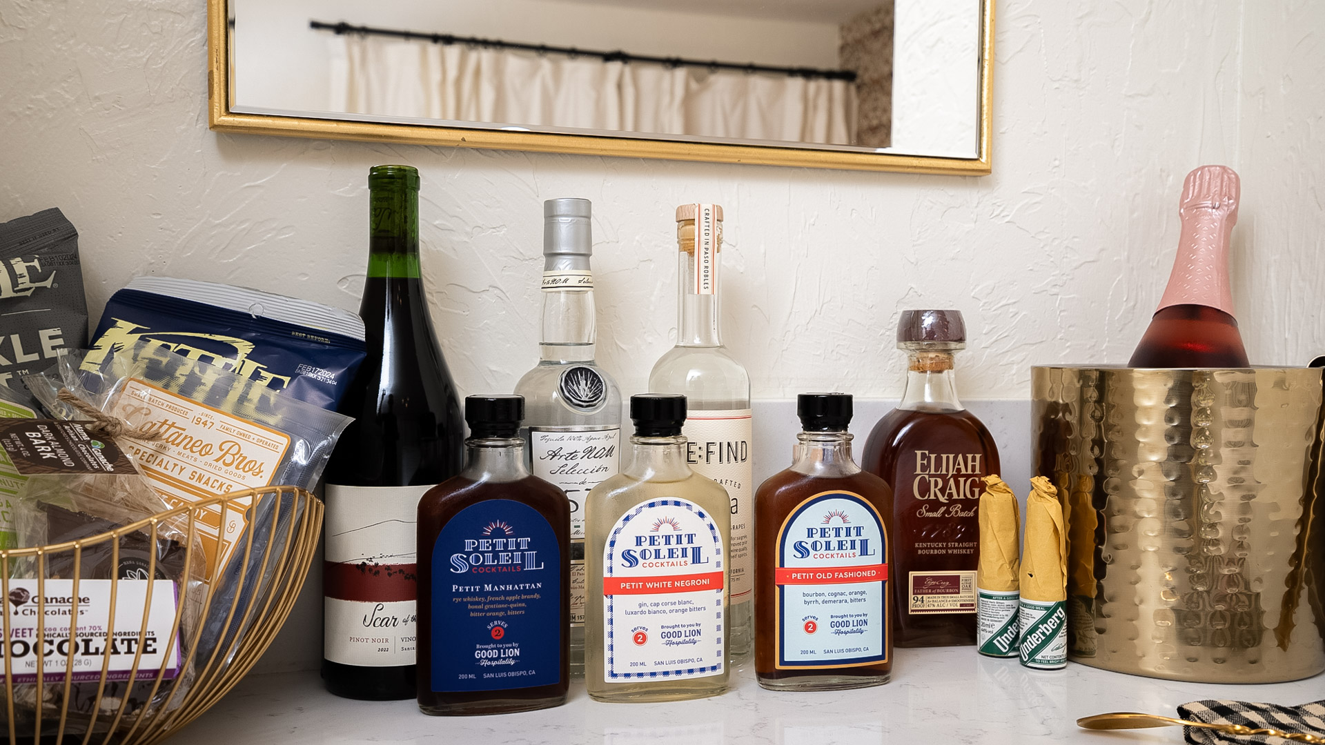 A bar setup with various bottles of alcohol, mixers, and snacks.