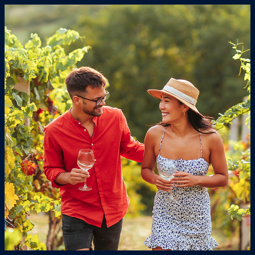 a man and woman walking in a vineyard