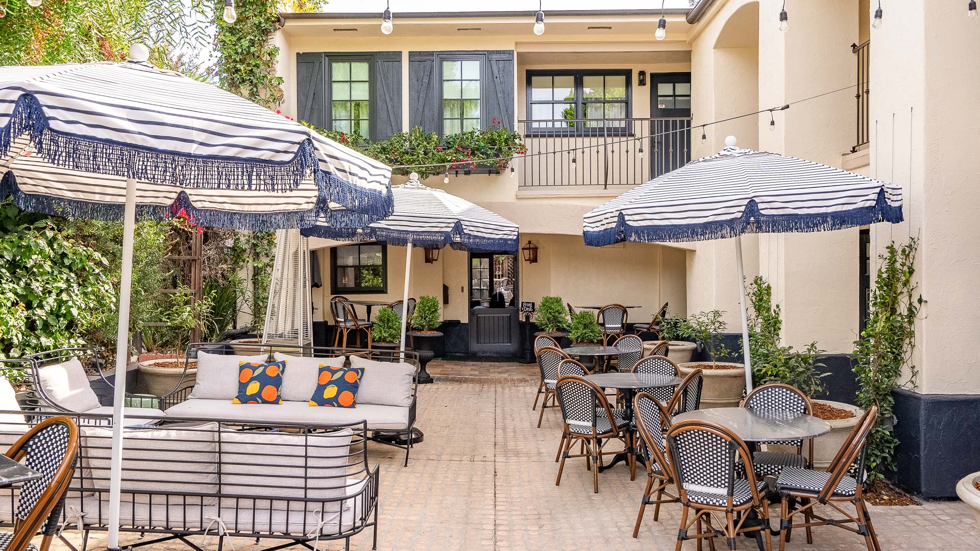A charming outdoor seating area with furniture, umbrellas, and plants.