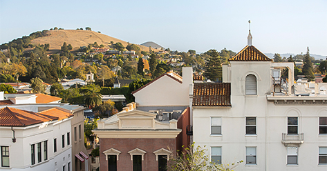 a group of buildings with trees and hills in the background