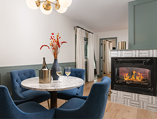 a room with a fireplace and a table with wine glasses