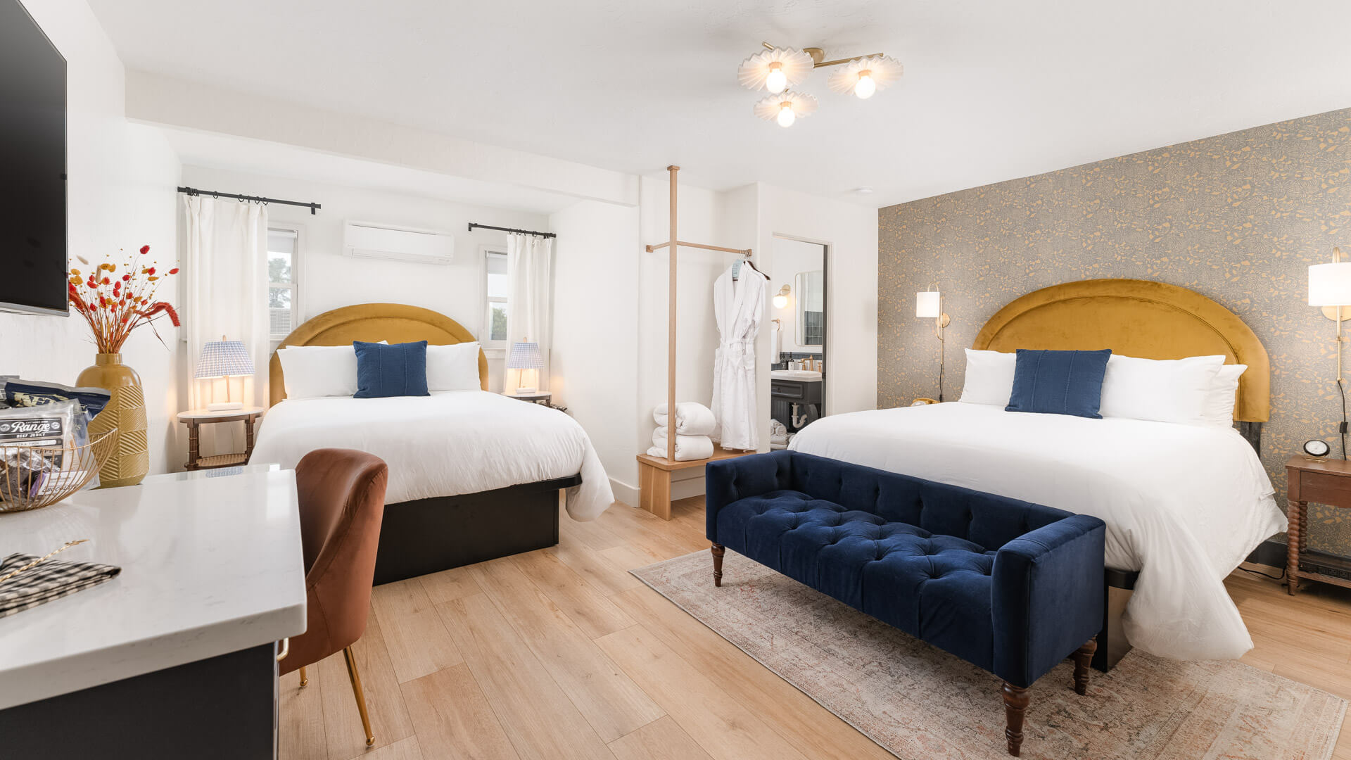 A hotel room with two beds, a desk, and a sofa.
