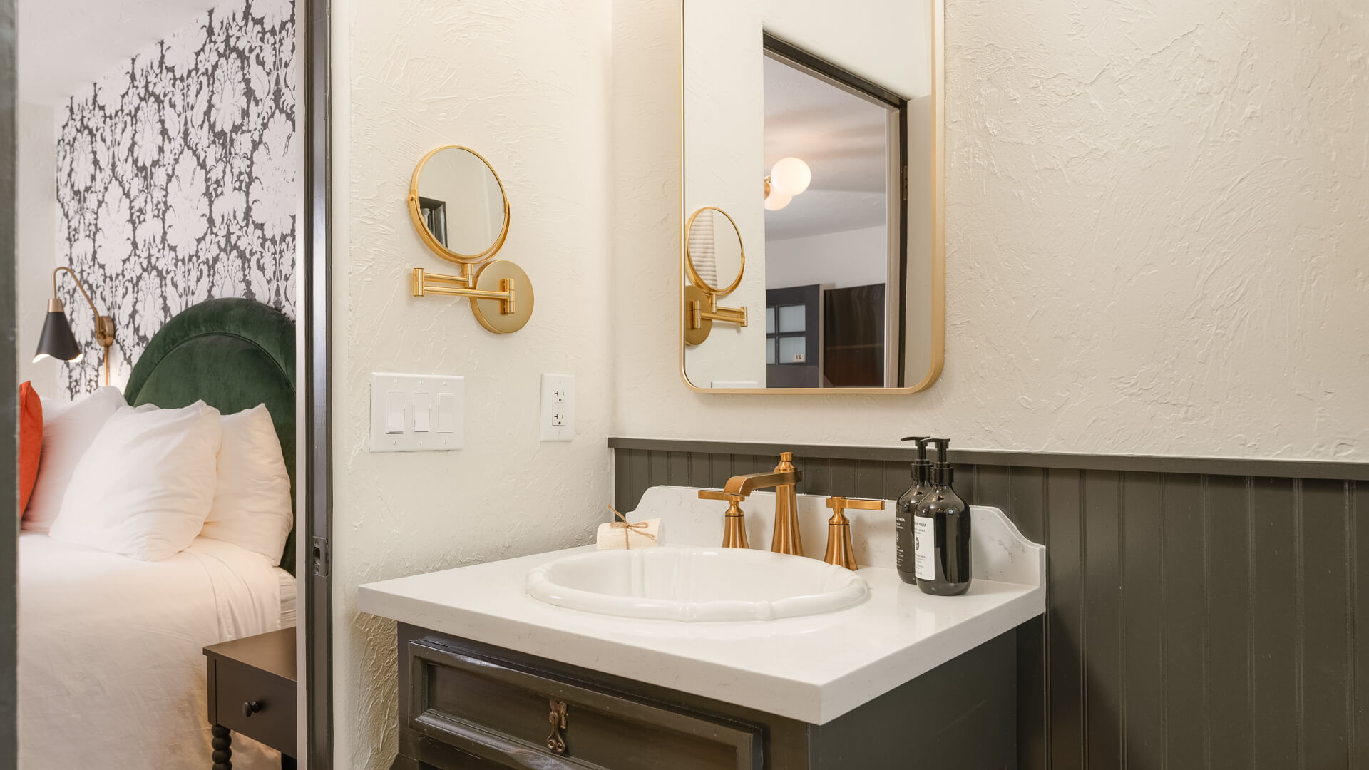 A bathroom sink area with a white sink, gold faucet, and round mirrors.
