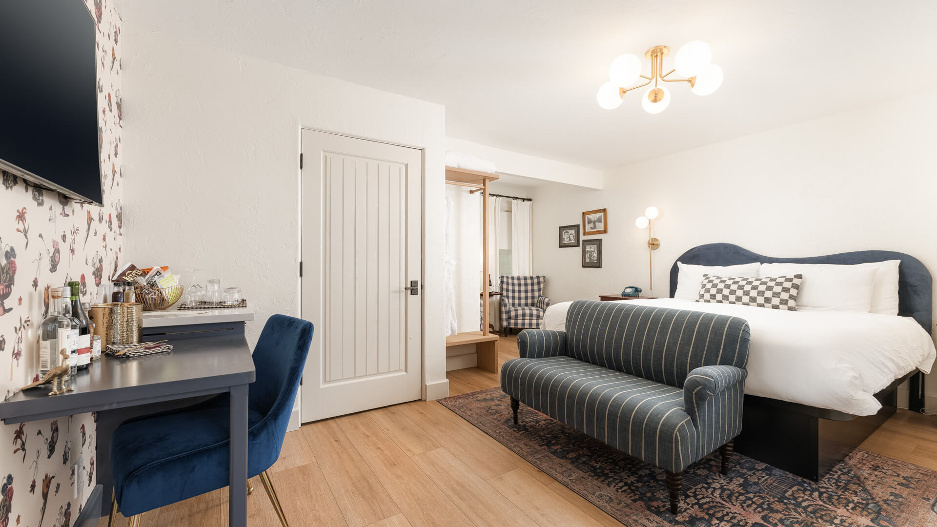 A wide view of a hotel room with a bed, sofa, desk, and chair.
