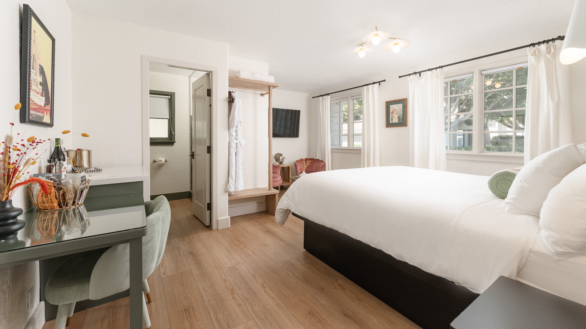 A wide view of a guest room with a bed, desk, chair, and TV.