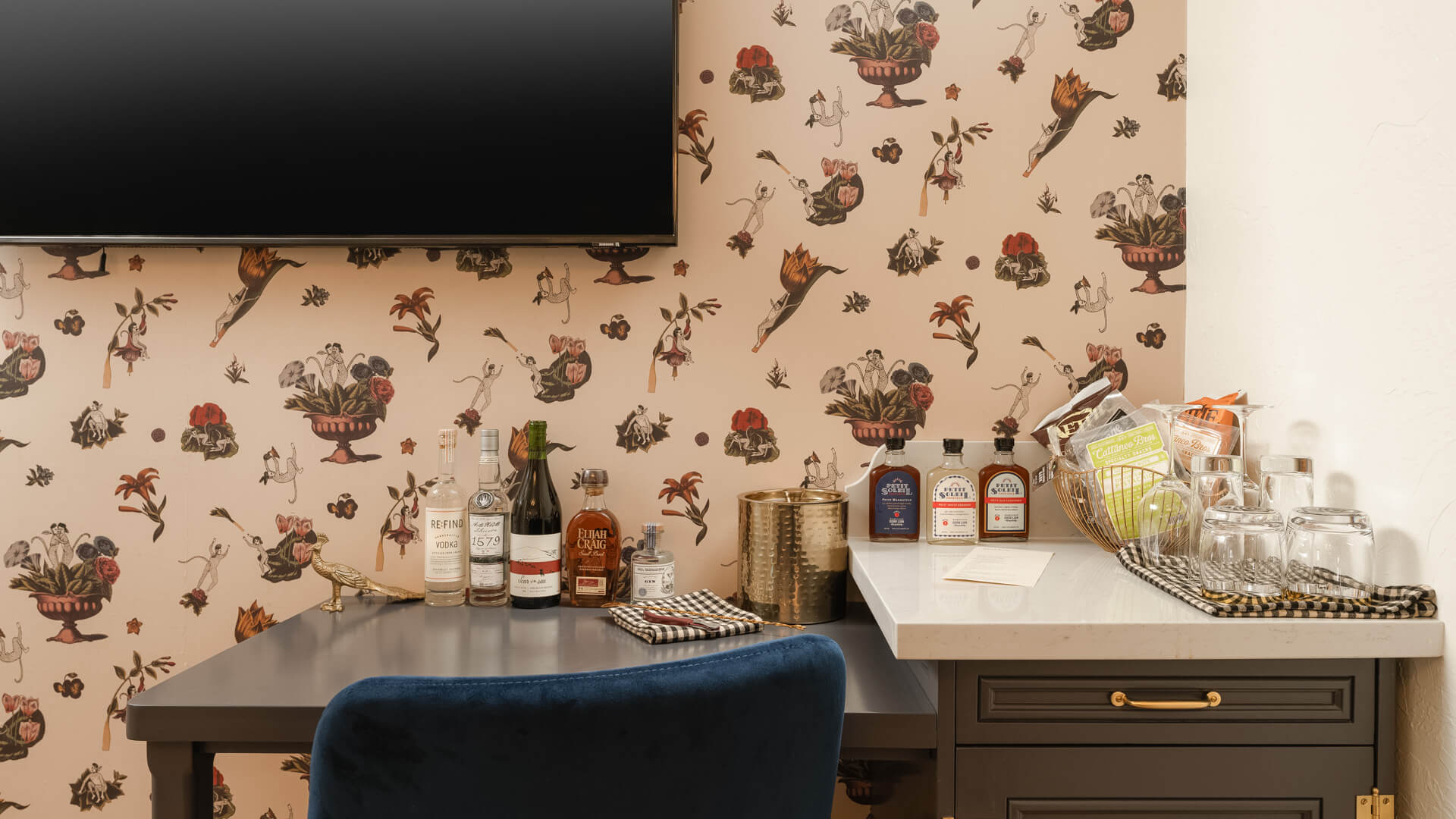A well-stocked wet bar with bottles, glasses, and a TV mounted on the wall.