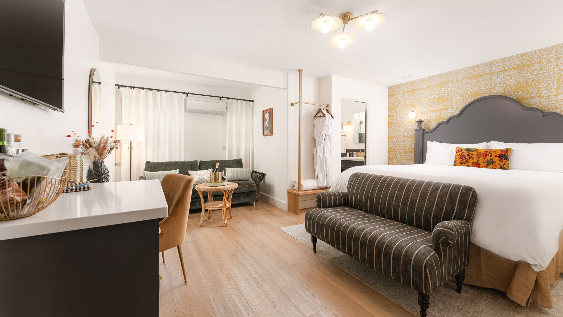 A wide view of a hotel room with a sofa bed, desk area, and TV.