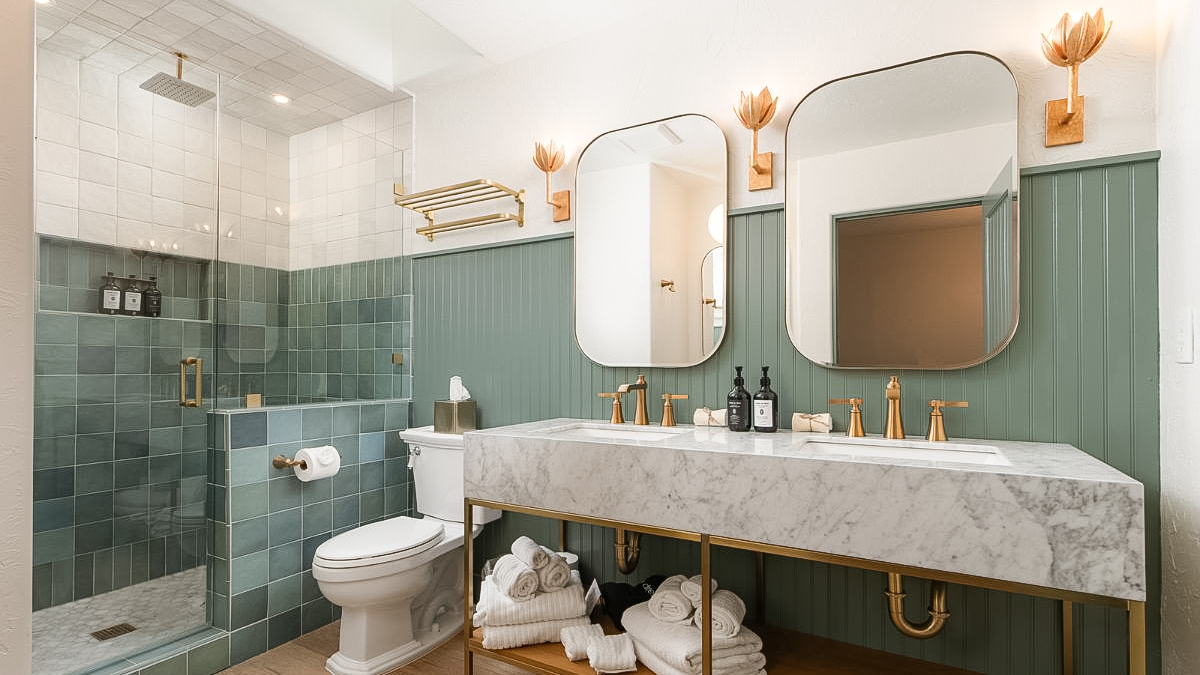 A modern bathroom with a large marble countertop, double sinks, and a glass-enclosed shower.