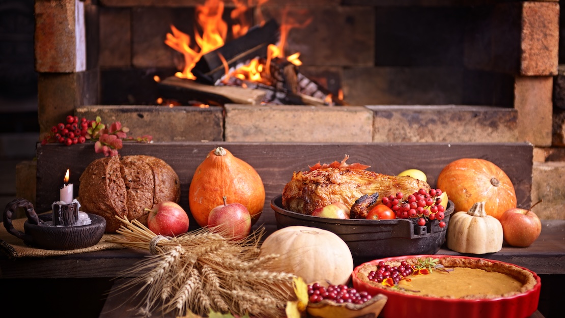 a table with food and a fire in the background