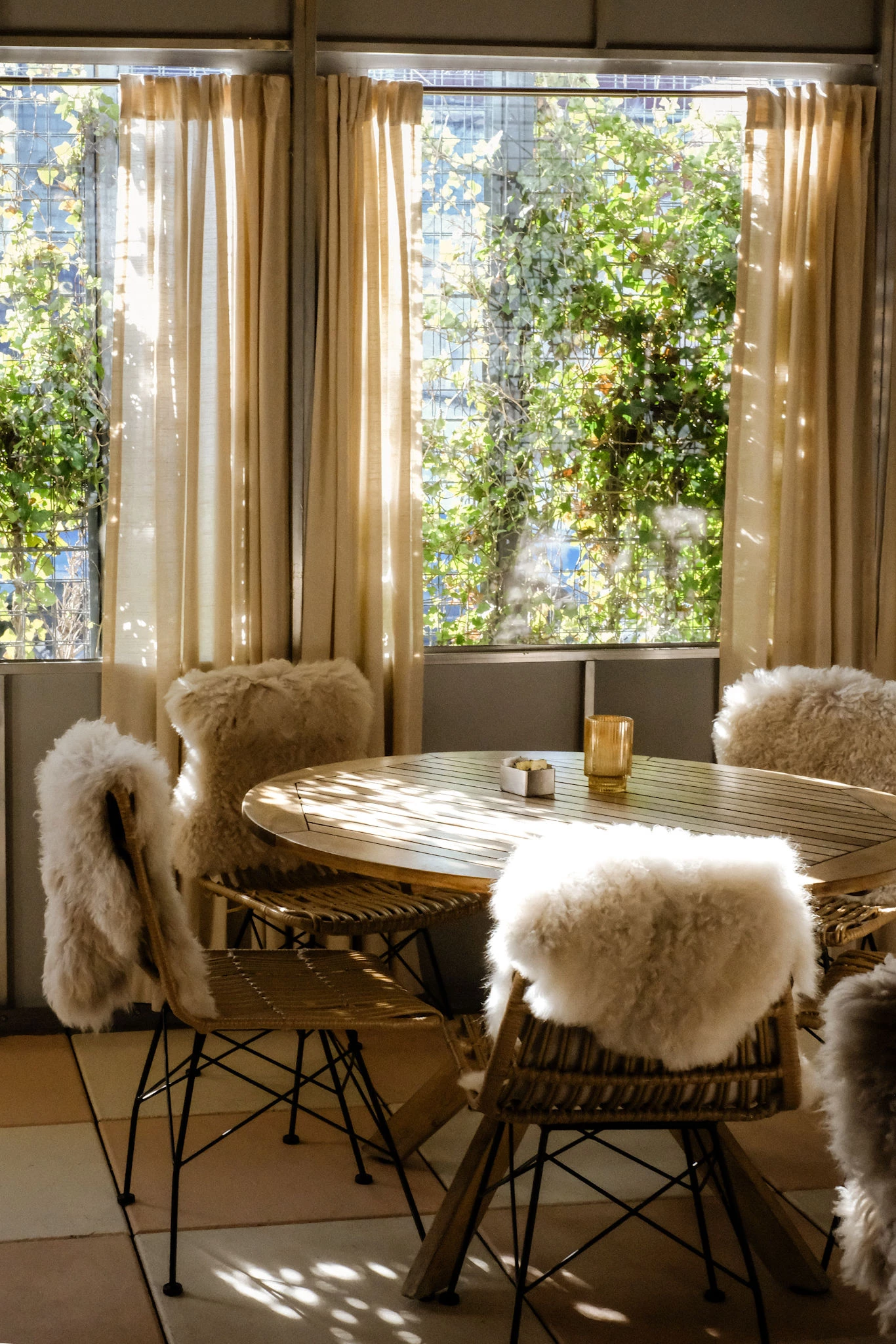 a table with fur chairs in a room with curtains and trees