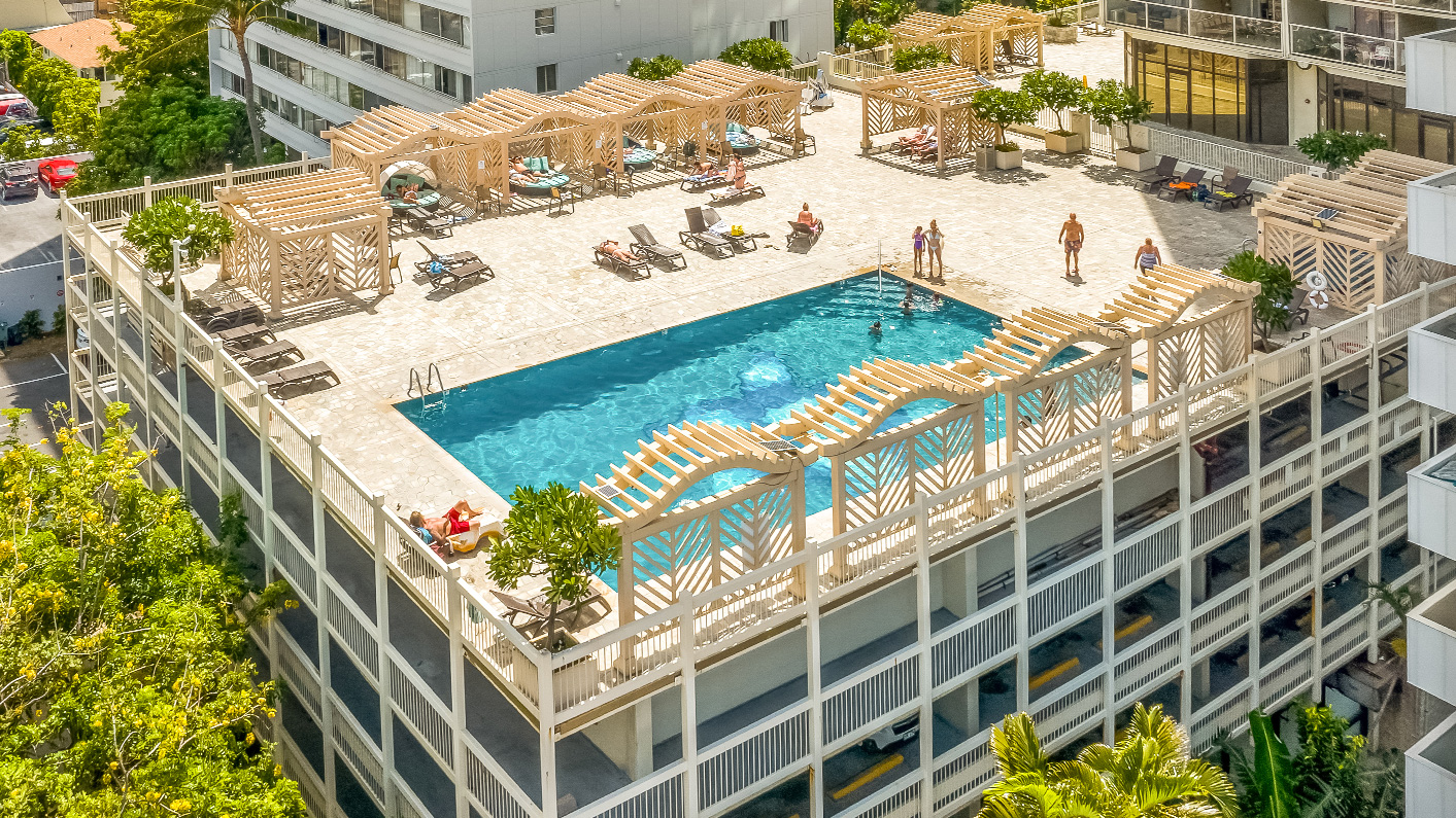 a pool with lounge chairs and umbrellas on top of a building