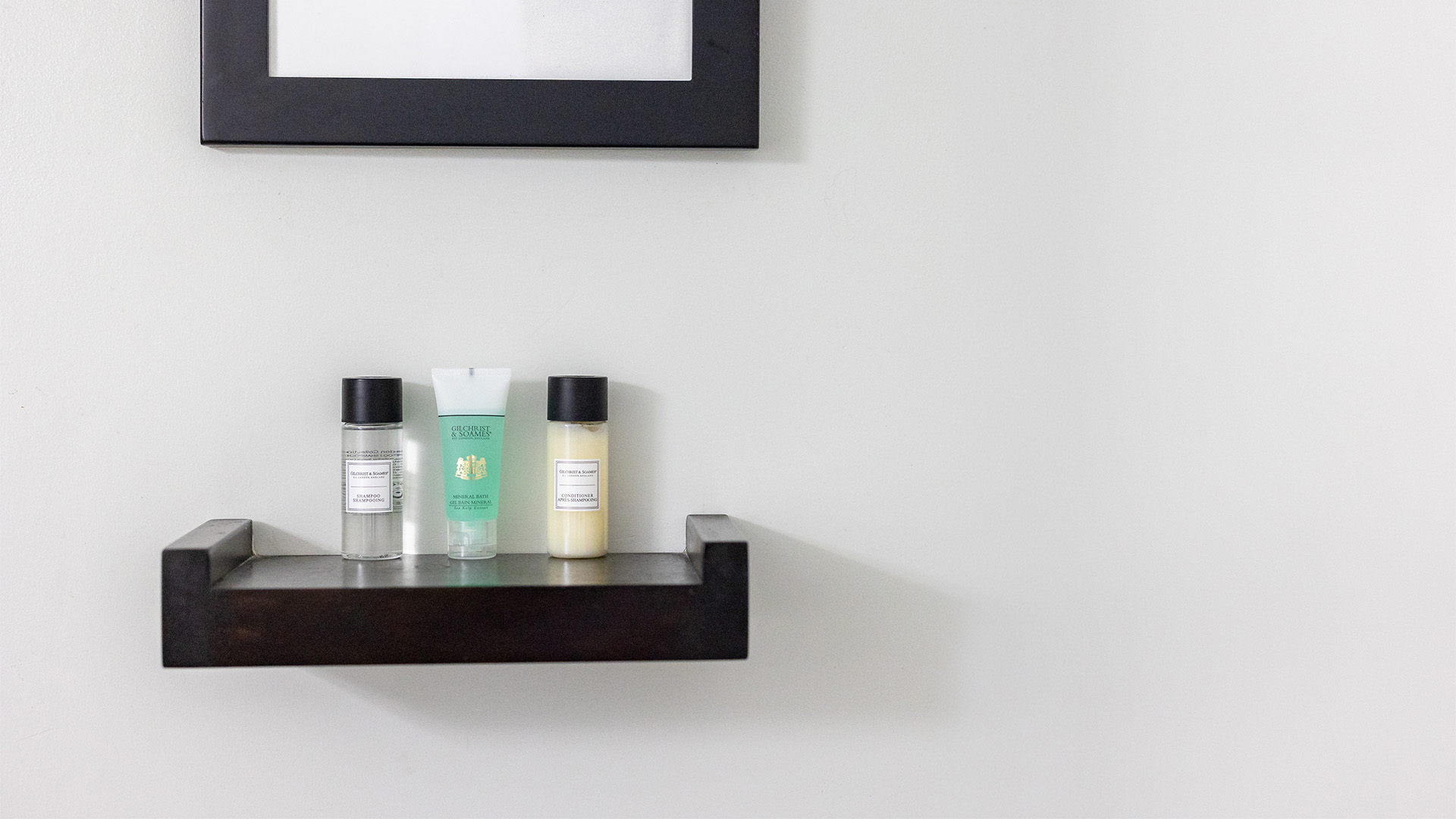 A small shelf with toiletries and a mirror on the wall.