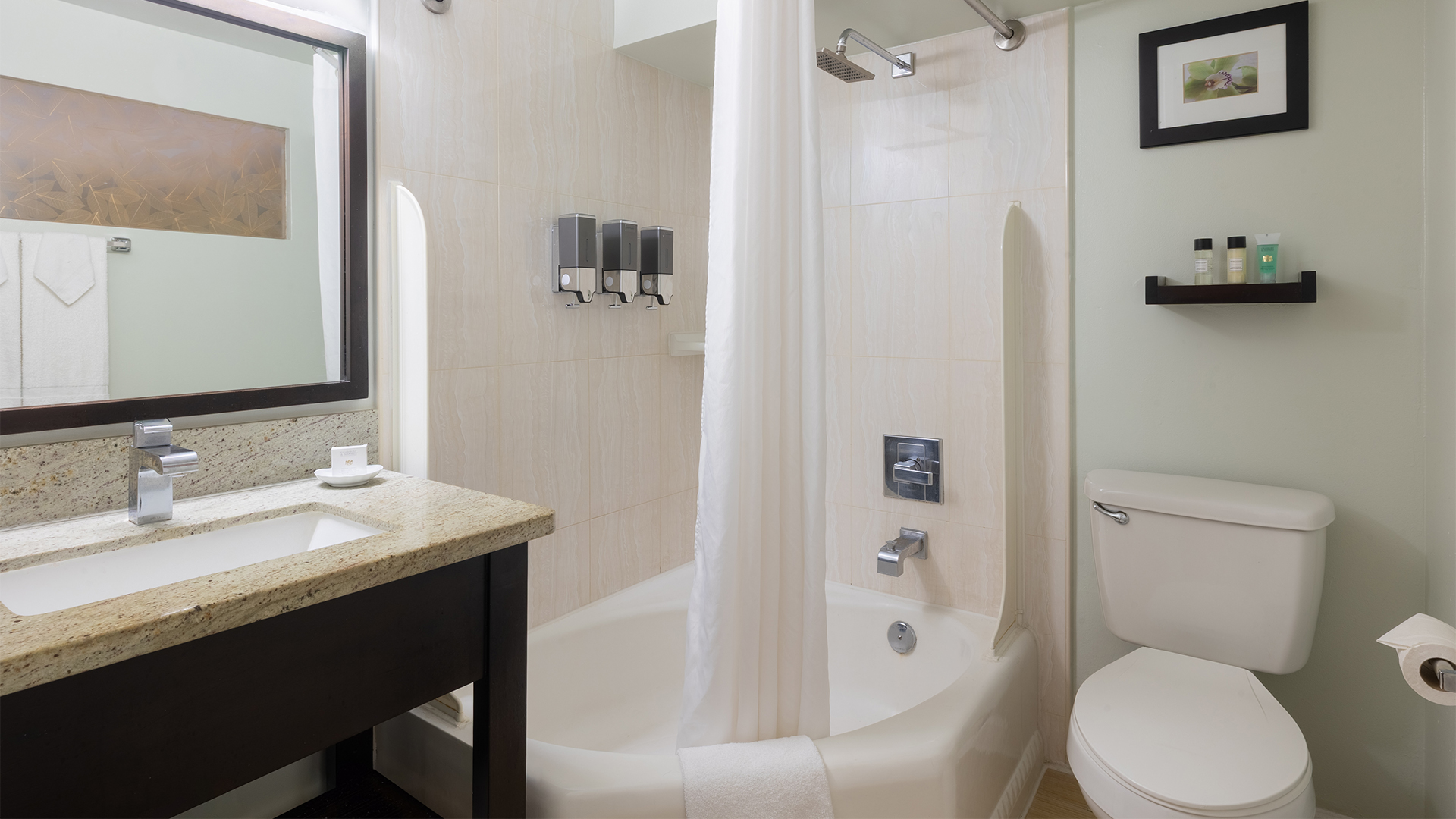 A clean bathroom with a sink, toilet, shower, and mirror