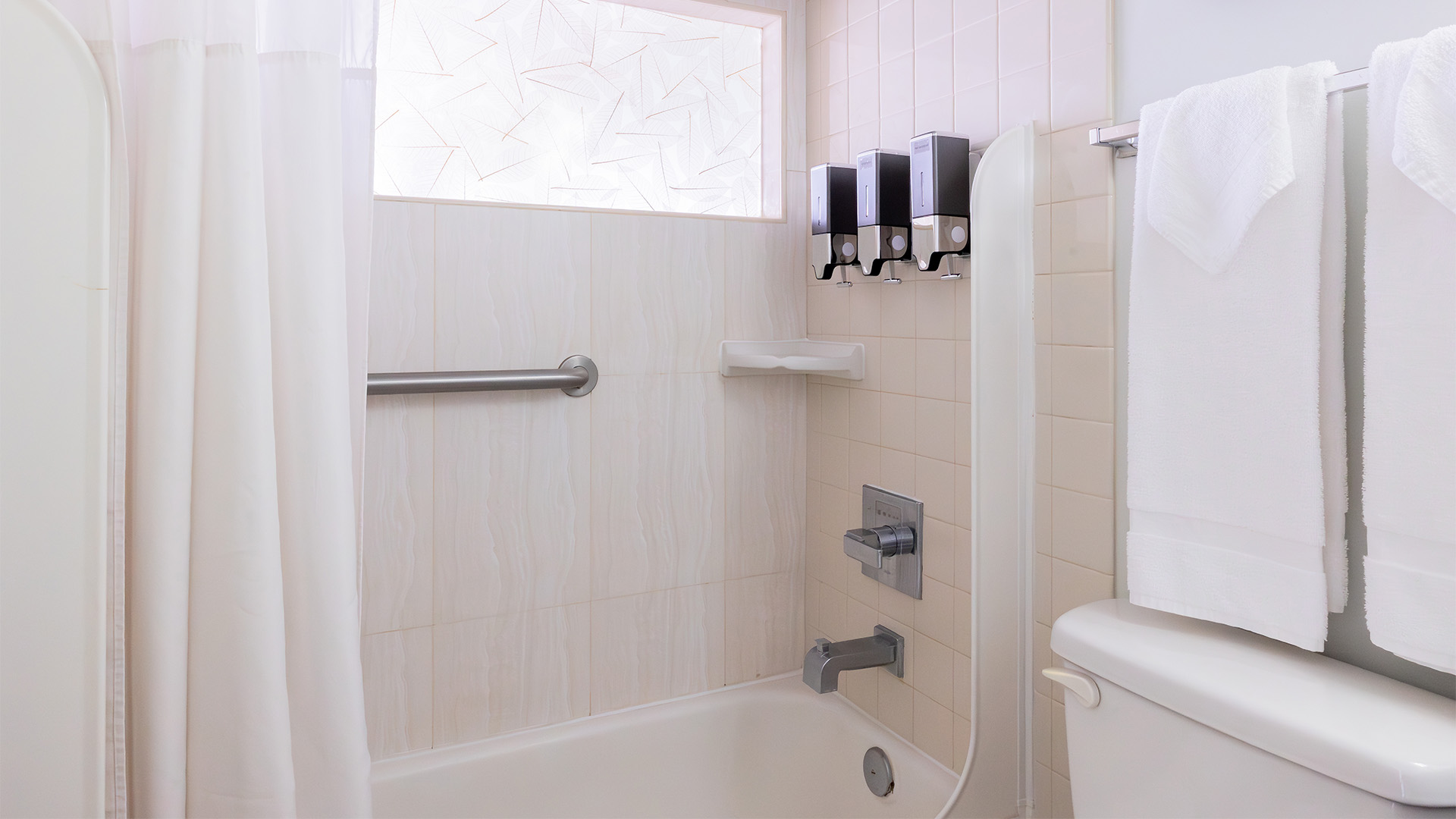 A clean bathroom with a bathtub, toilet, and towels.