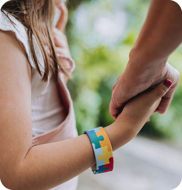 a child holding a hand with a puzzle piece bracelet