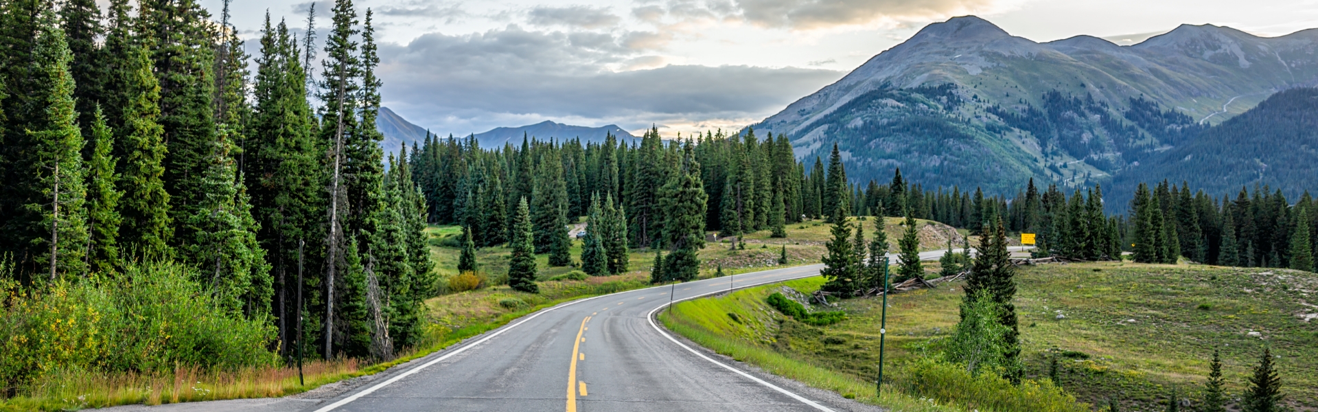 a road with trees and mountains in the background