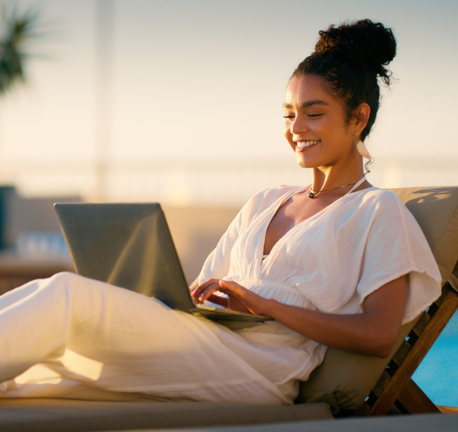 a woman sitting on a lounge chair with a laptop