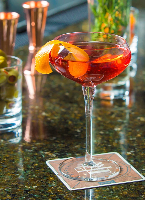 a glass with a drink and a slice of orange on it