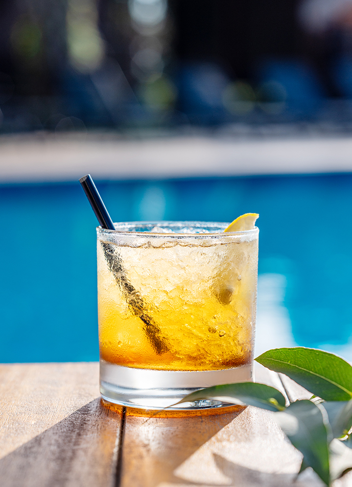 a glass of drink with a straw and a slice of lemon