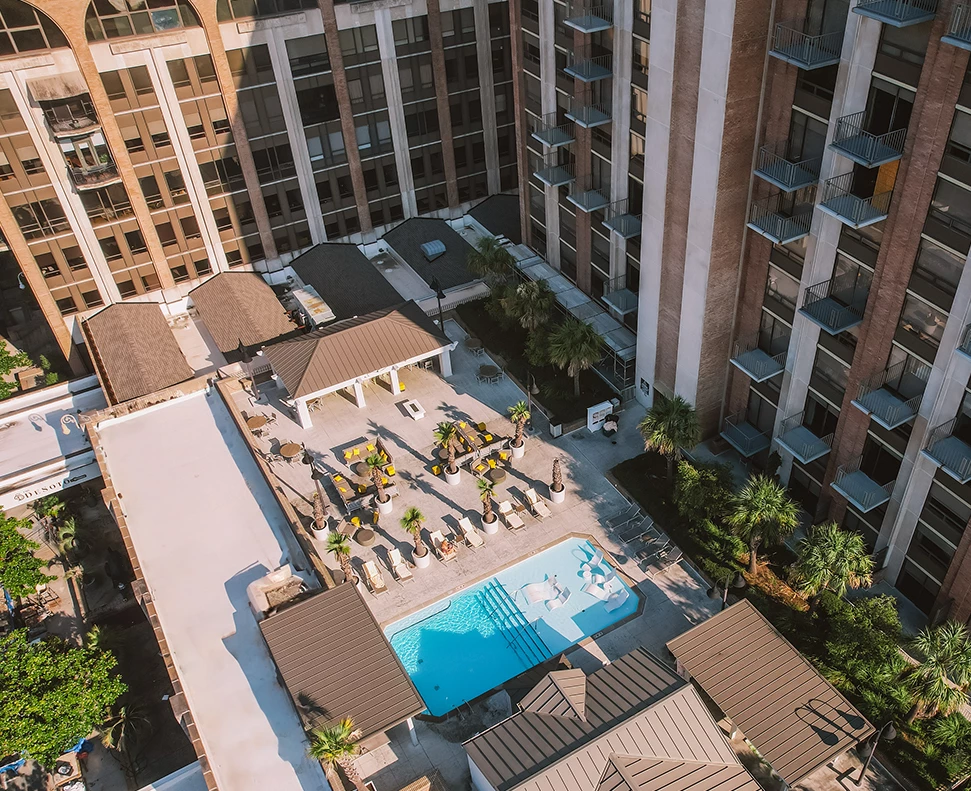 Aerial view of a hotel pool area with lounge chairs and palm trees