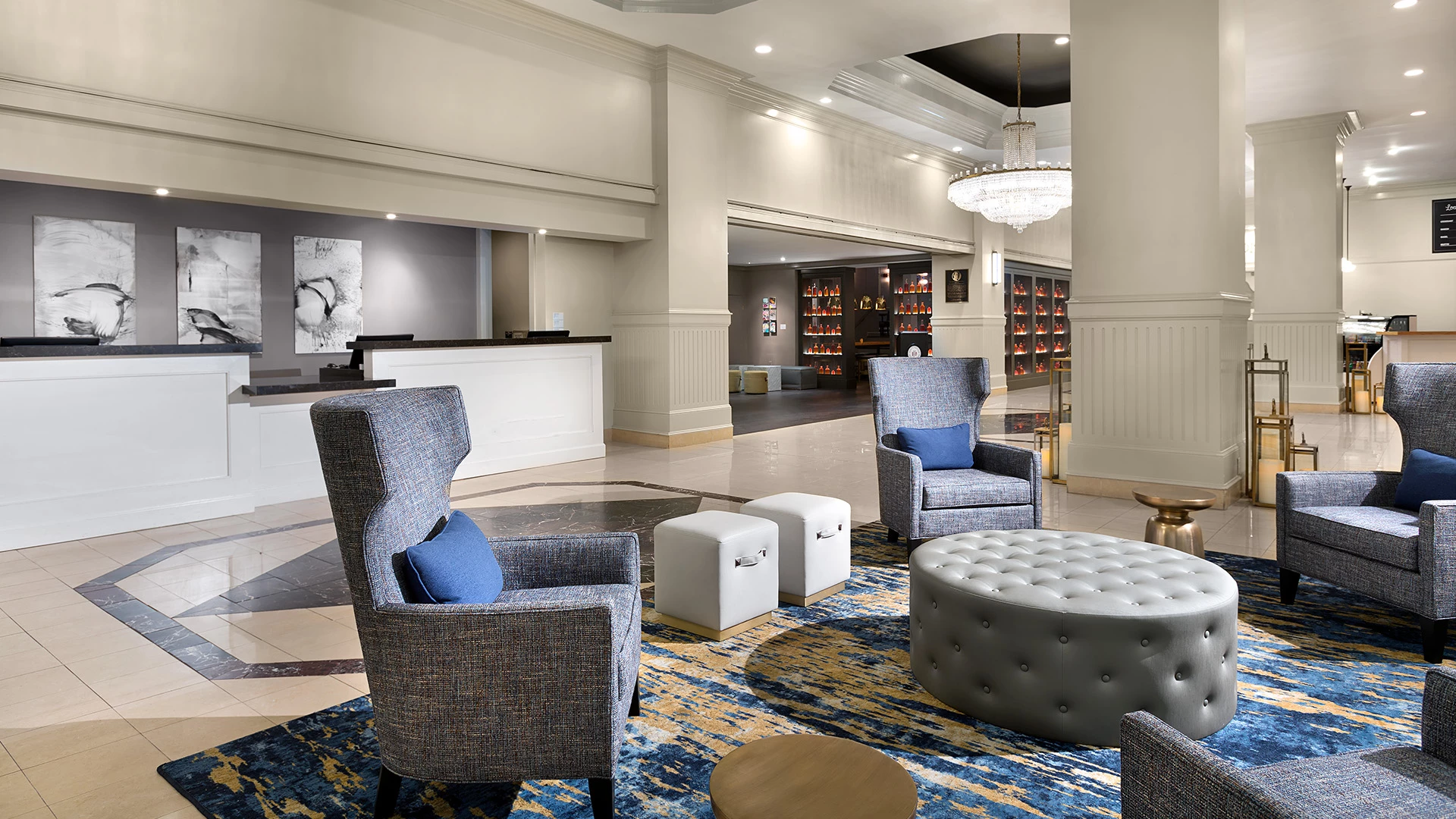 A hotel lobby with a reception desk, seating area, and chandelier