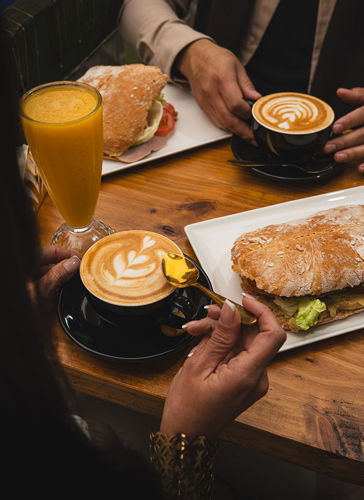 a person holding a spoon over a sandwich