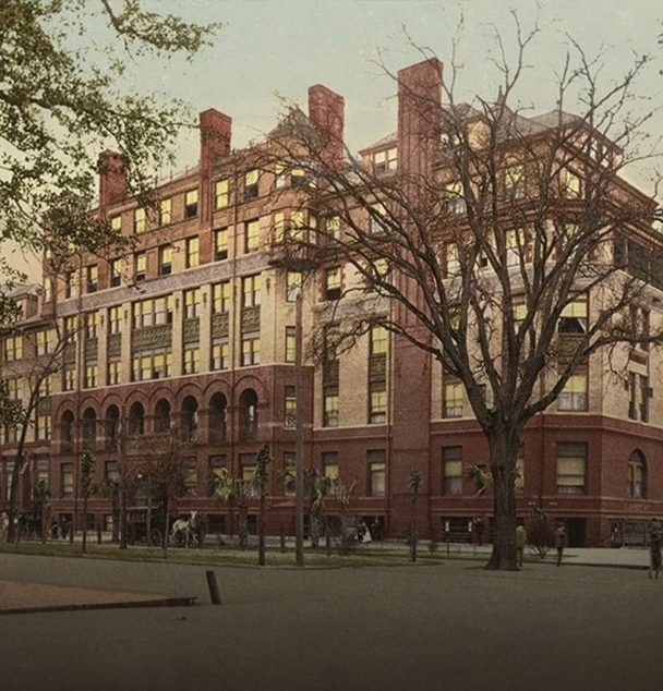 a large building with trees and people walking around