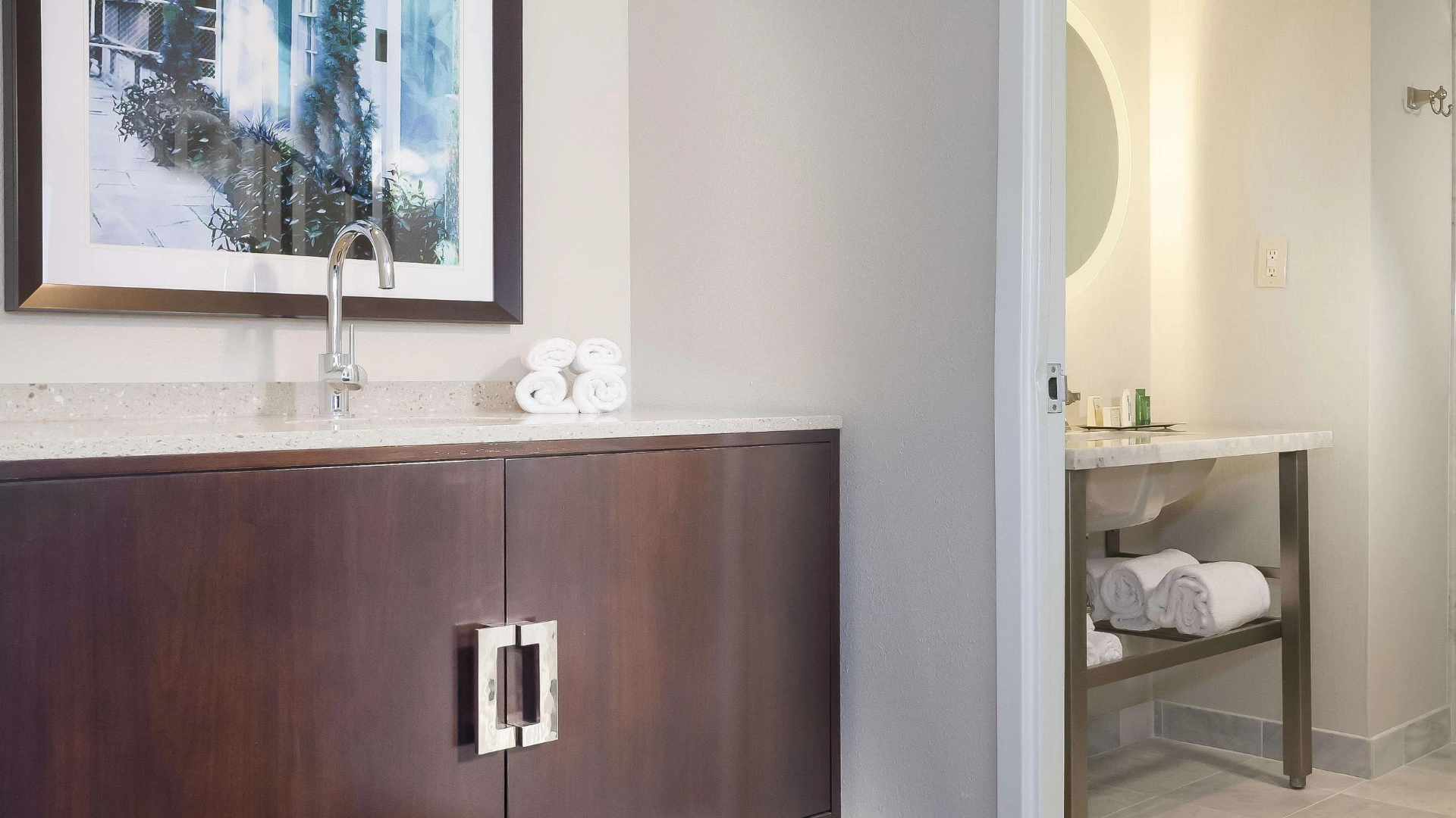 A modern bathroom with a granite countertop, wood cabinet, and tiled floor