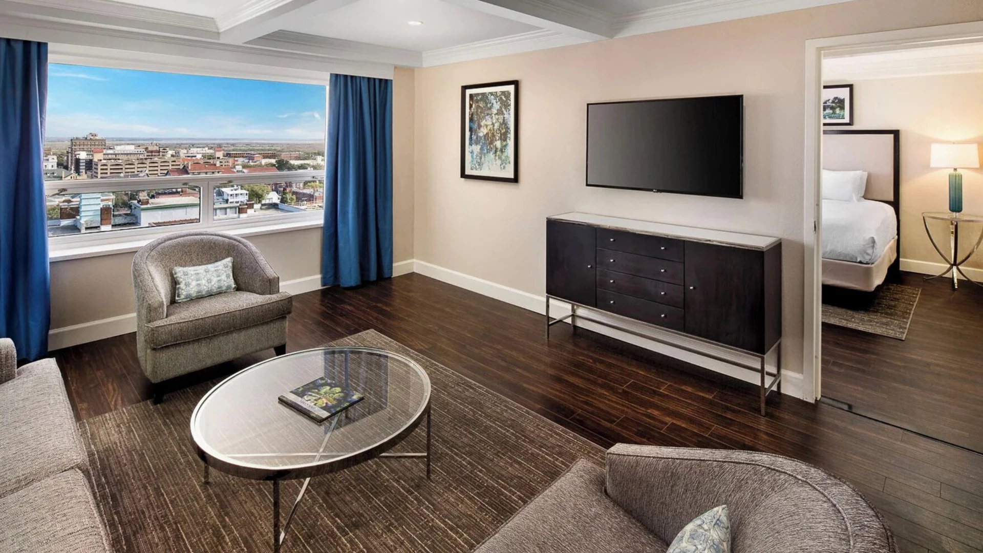A wide view of a hotel suite with a living area and a bedroom in the background.