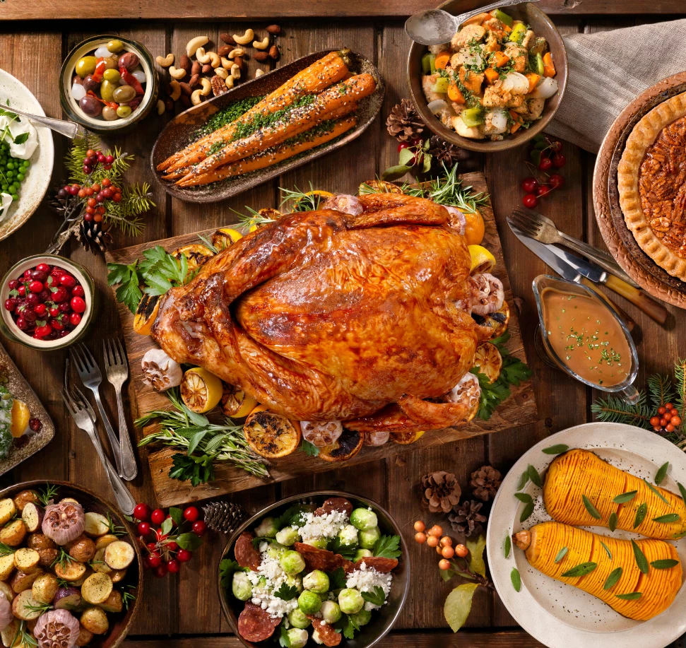 A festive holiday spread featuring a roasted turkey, various side dishes, and pumpkin pie on a wooden table.