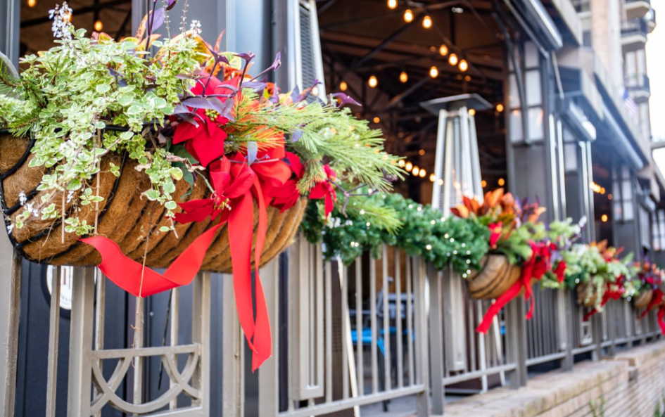 a planter with red bows and ribbons on a fence