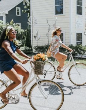 two women riding bicycles on a street