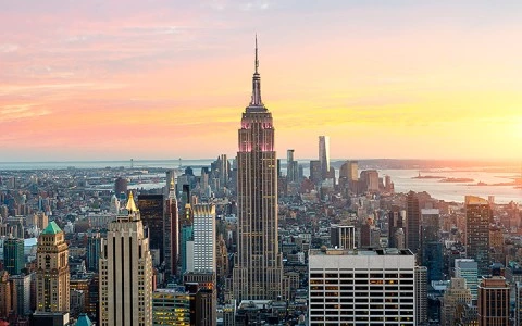 A cityscape at sunset with skyscrapers and a prominent building in the center