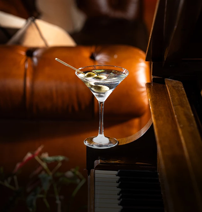 a martini glass with olives on a piano