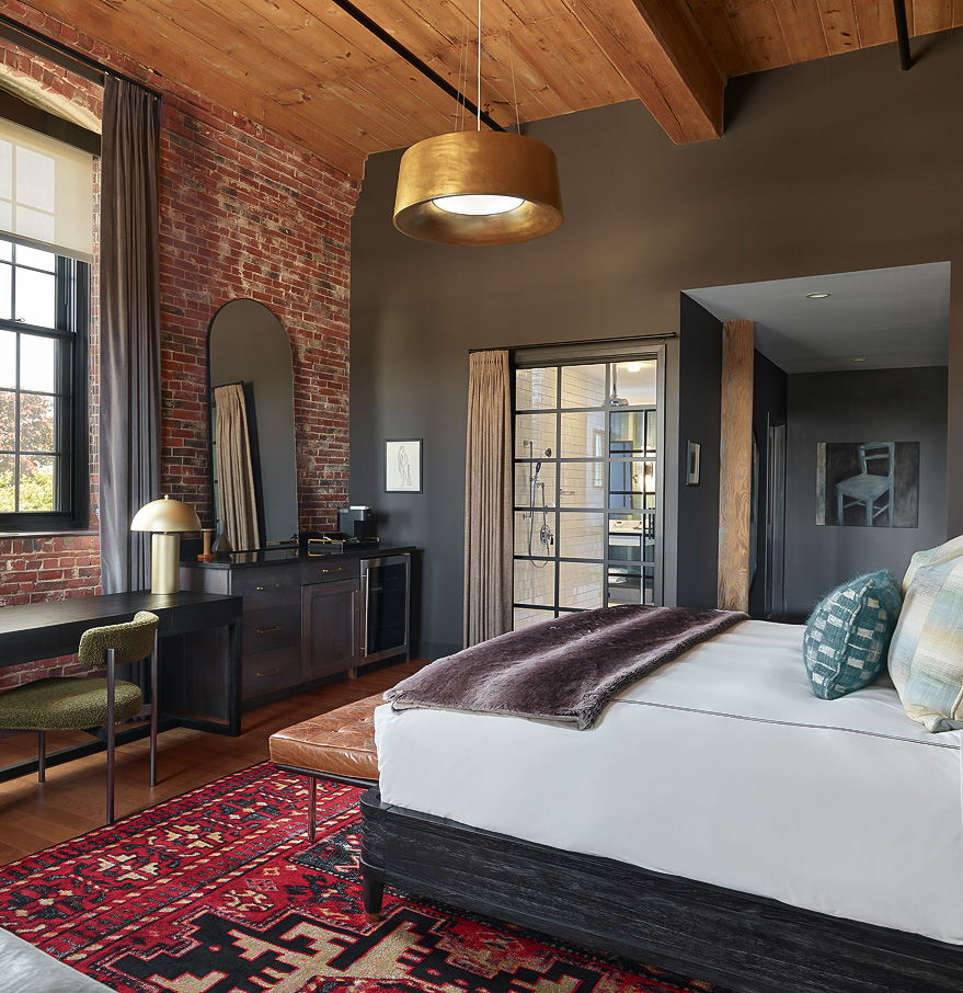 a bedroom with a brick wall and a bed and a desk