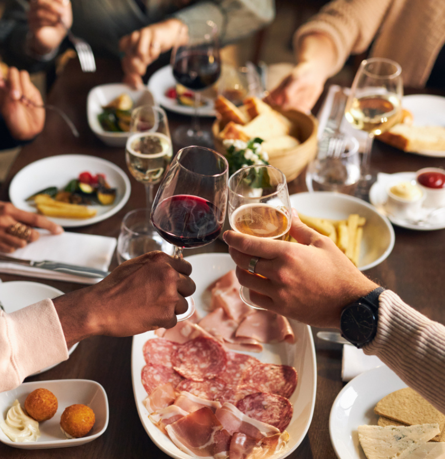 a group of people clinking glasses of wine at a table with food