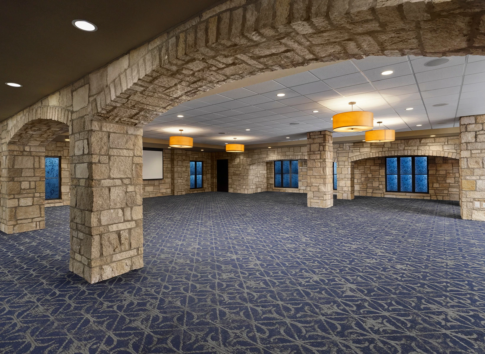 a large room with stone pillars and blue carpet