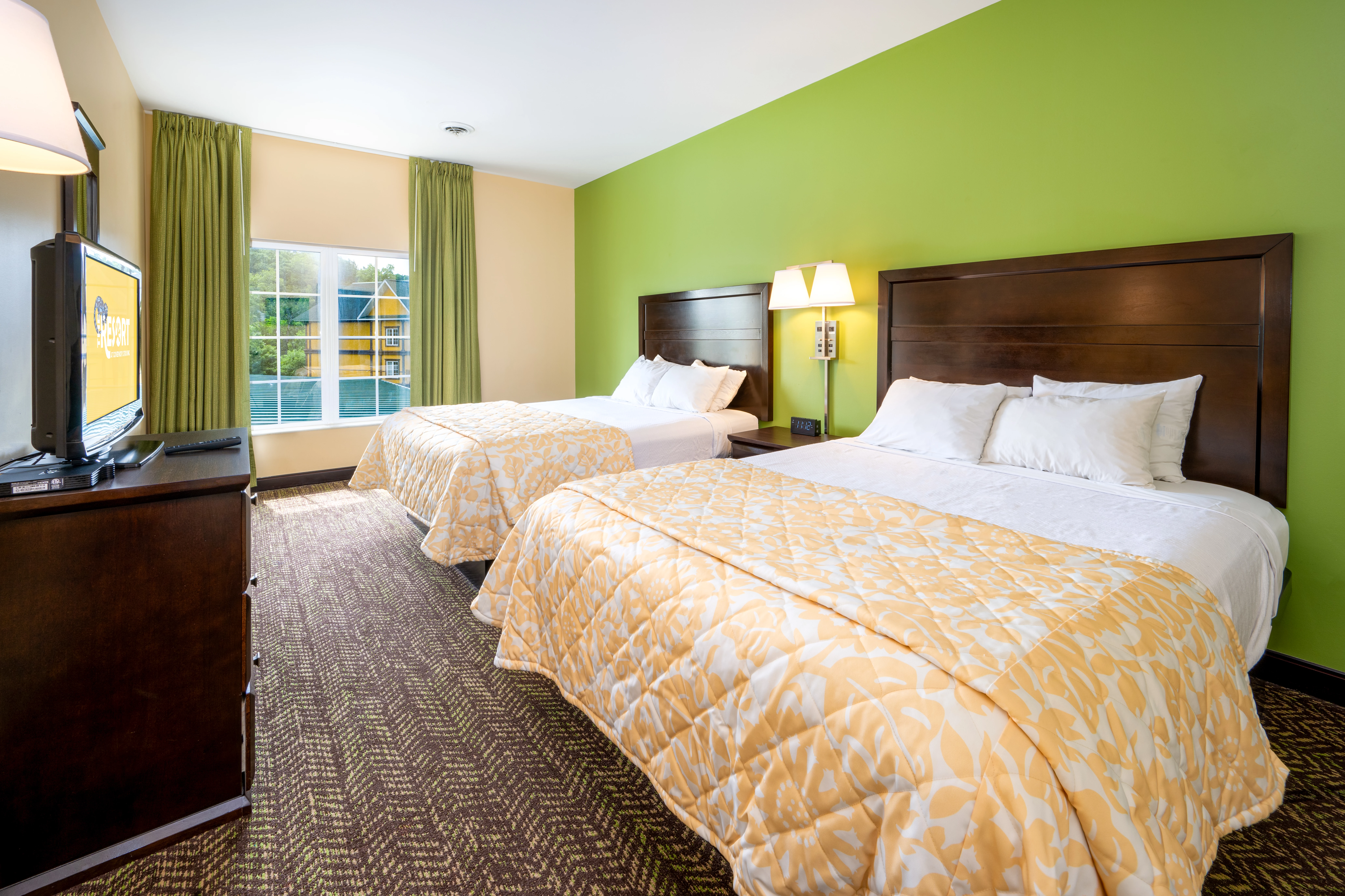 A hotel room with two beds, a TV, and a window.