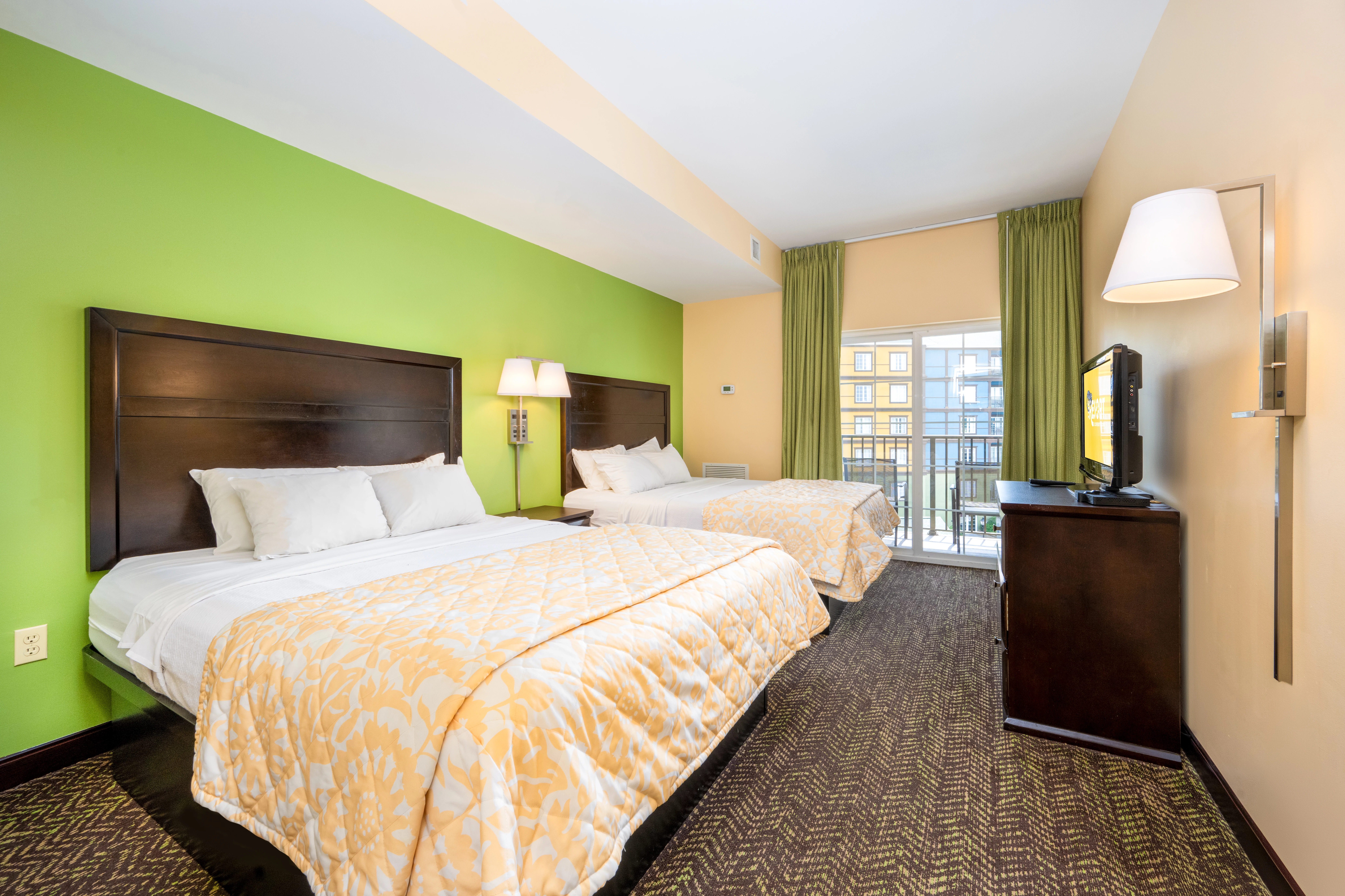A hotel room with two beds, a TV, and a balcony.