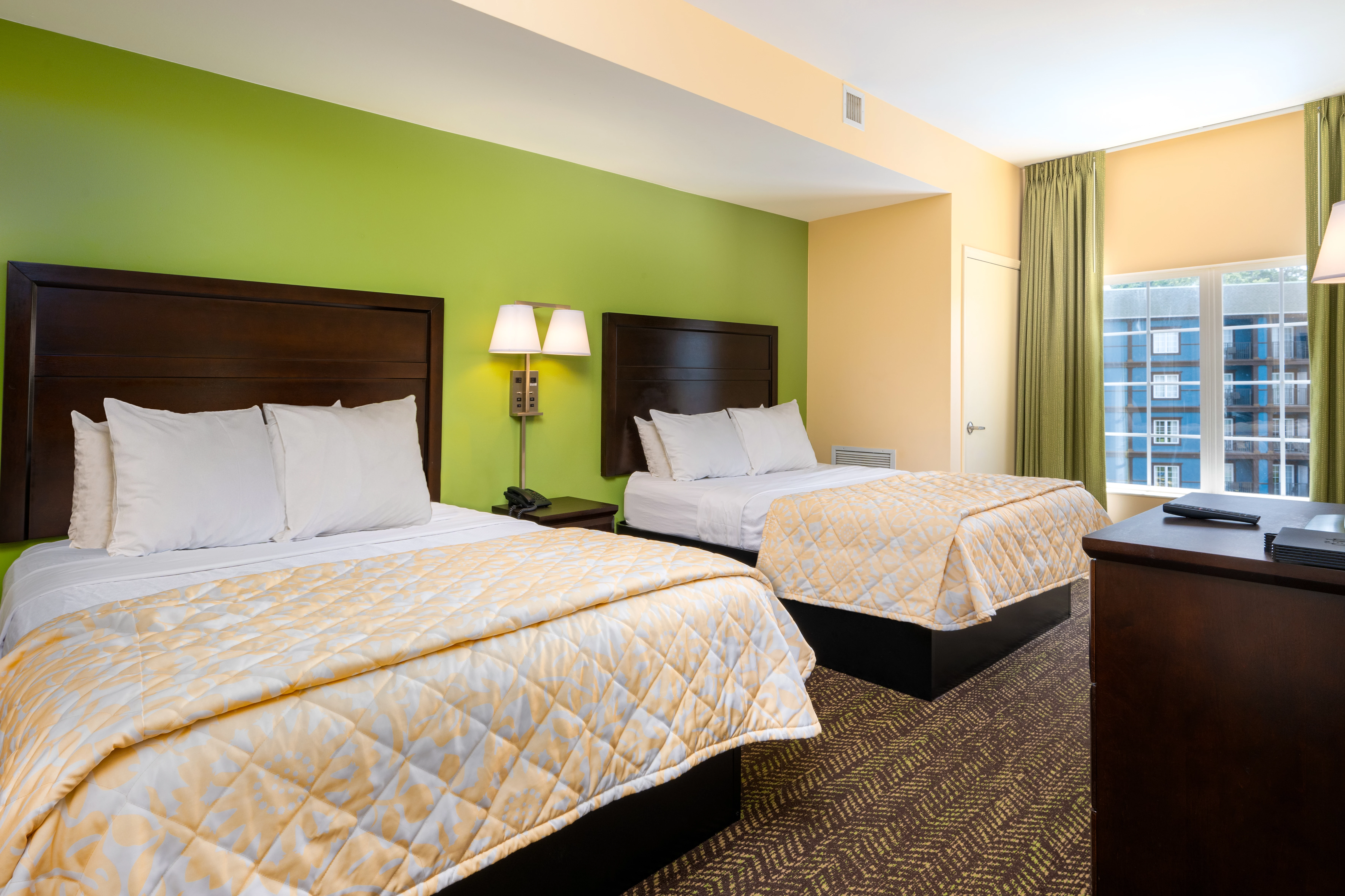 A hotel room with two twin beds, a desk, and a window