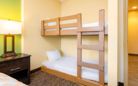 A compact room with a bunk bed, desk, and lamp.