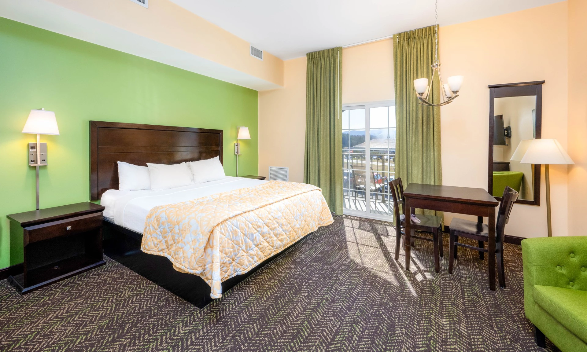 A hotel room with a king-sized bed, desk, and balcony access.