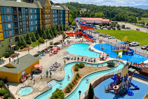 An aerial view of a water park with a large pool, water slides, and a parking lot.