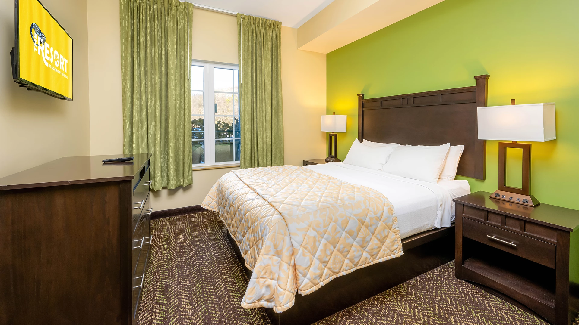 A hotel room with a bed, TV, and window