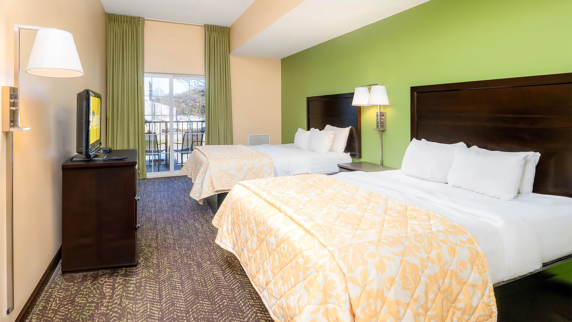 A hotel room with two double beds, a TV, and a balcony